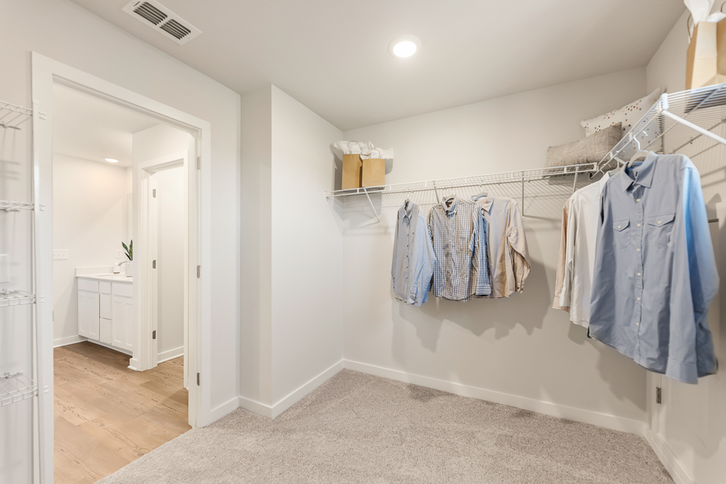 A room with a white wall and a white door with a row of clothes on it.