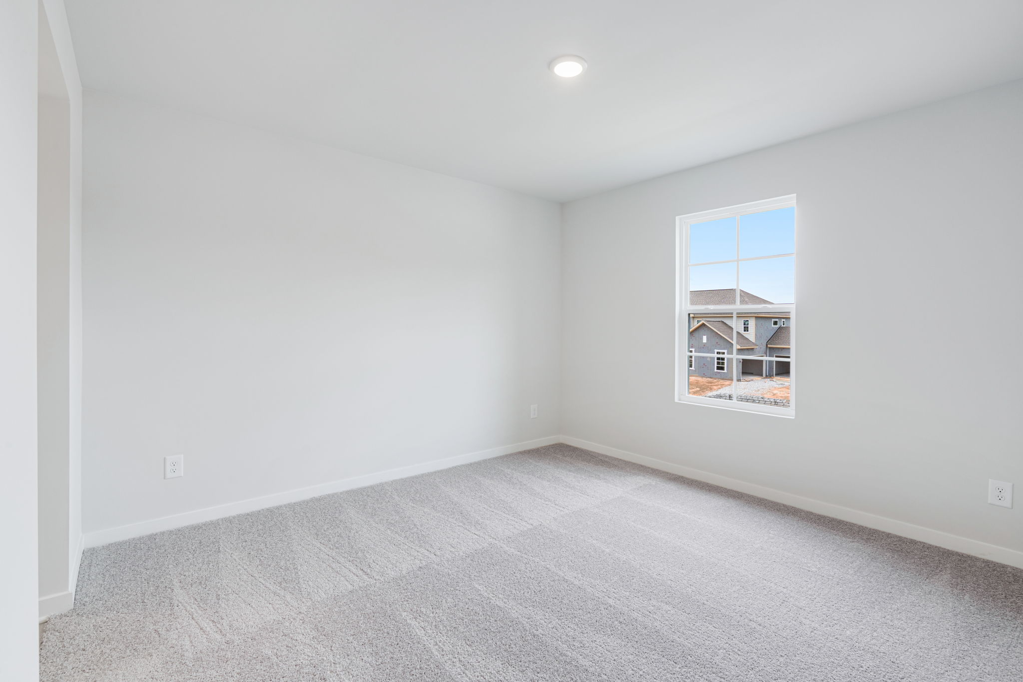 A room with a window and a white wall.