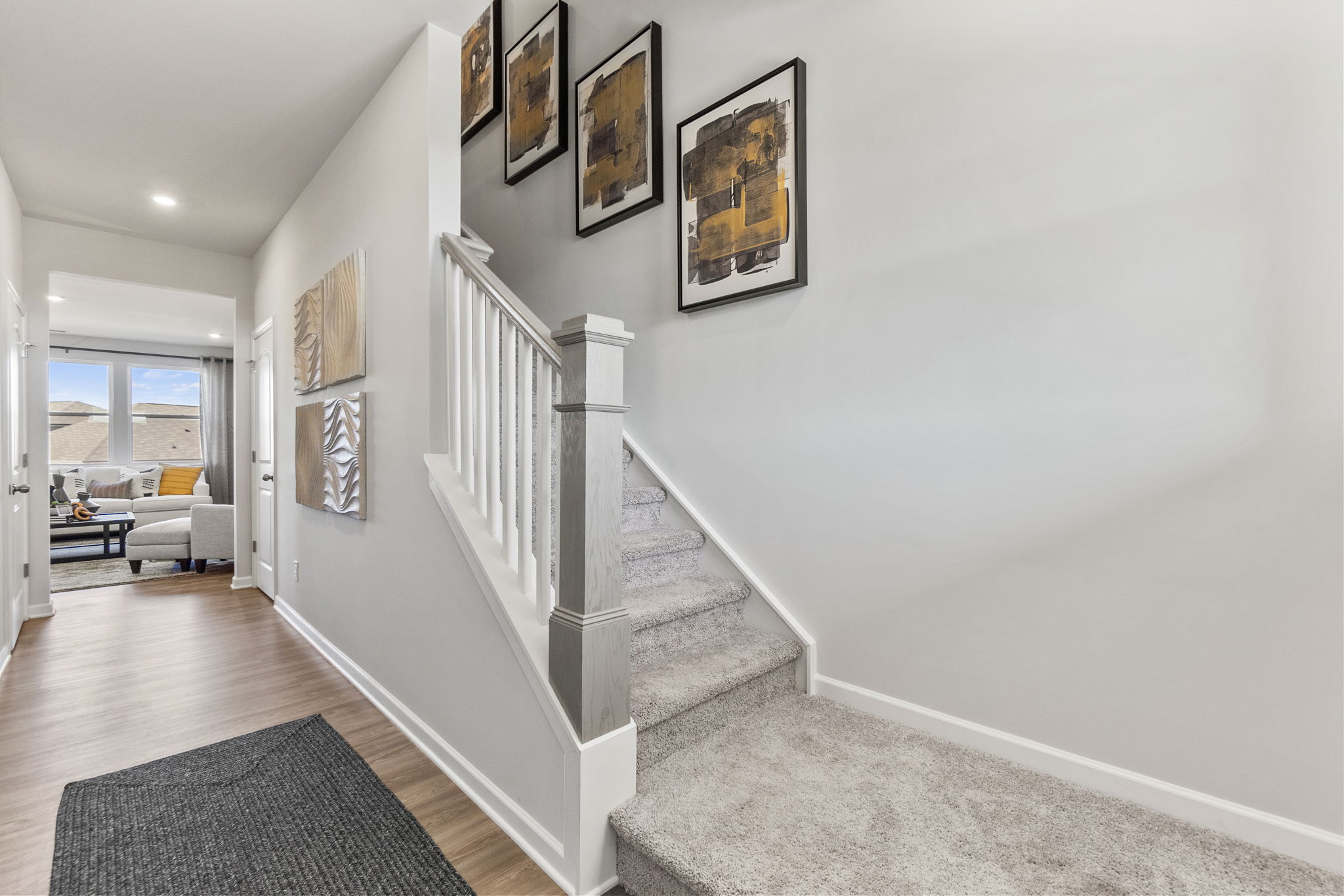 A white staircase with pictures on the wall.