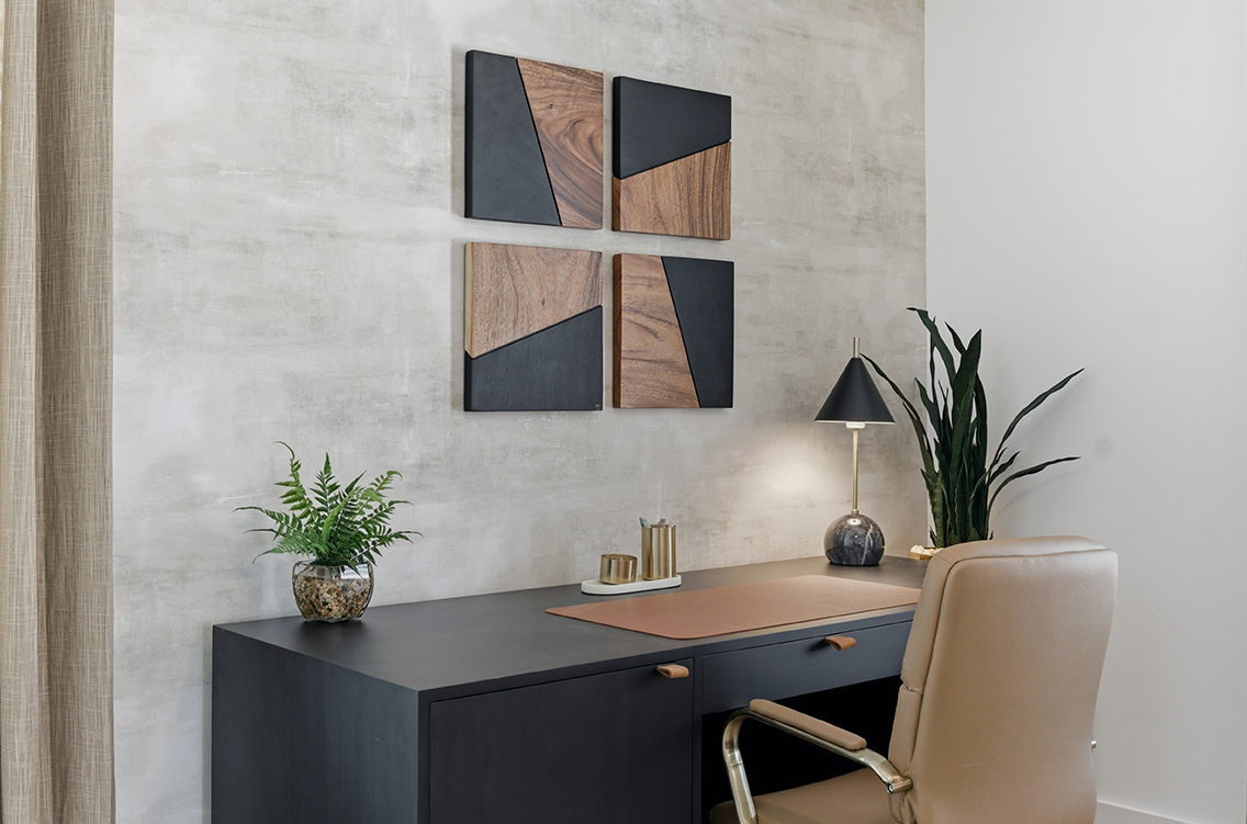 A desk with a lamp and a chair in a room with a wall with pictures on it.