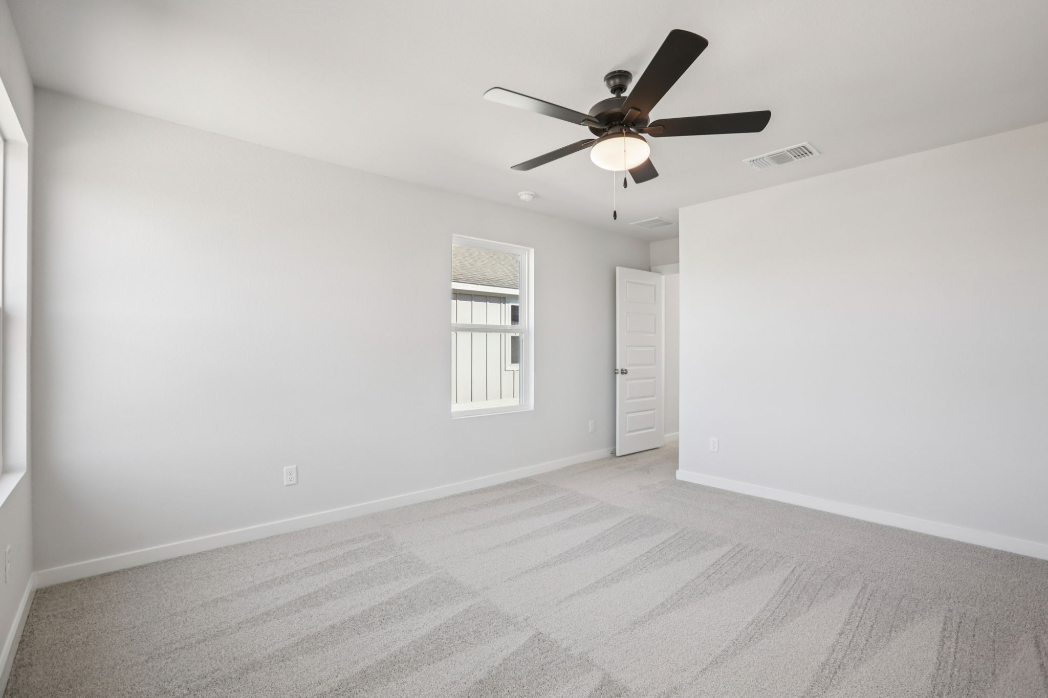 A room with a ceiling fan and a door.