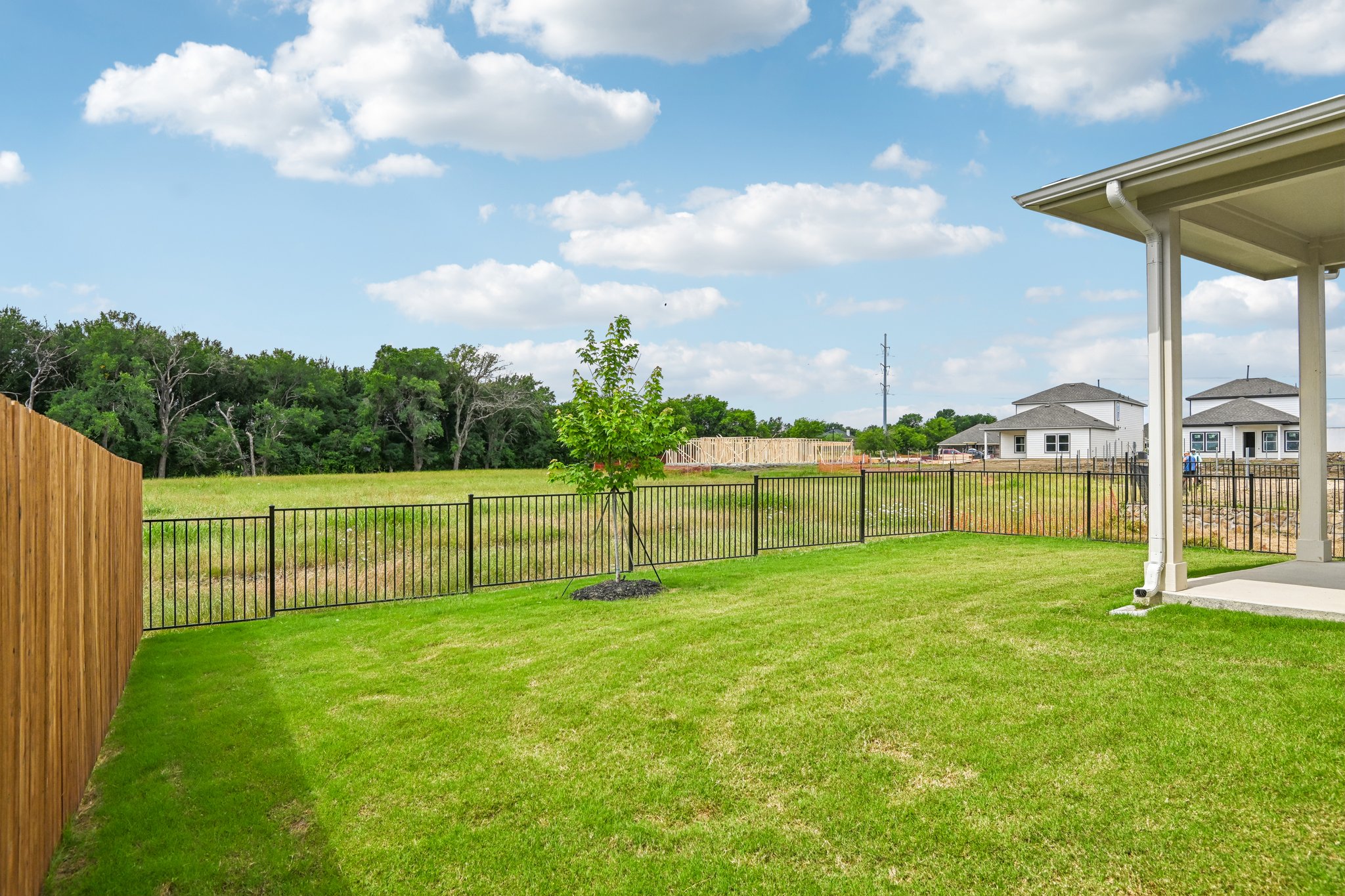 A fenced in yard with a wood gate and a house in the background.