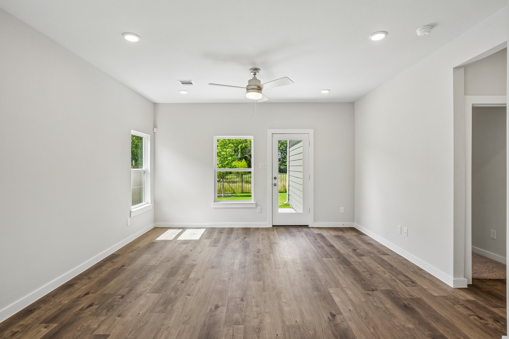 A room with a wood floor and a wood floor with a ceiling fan.