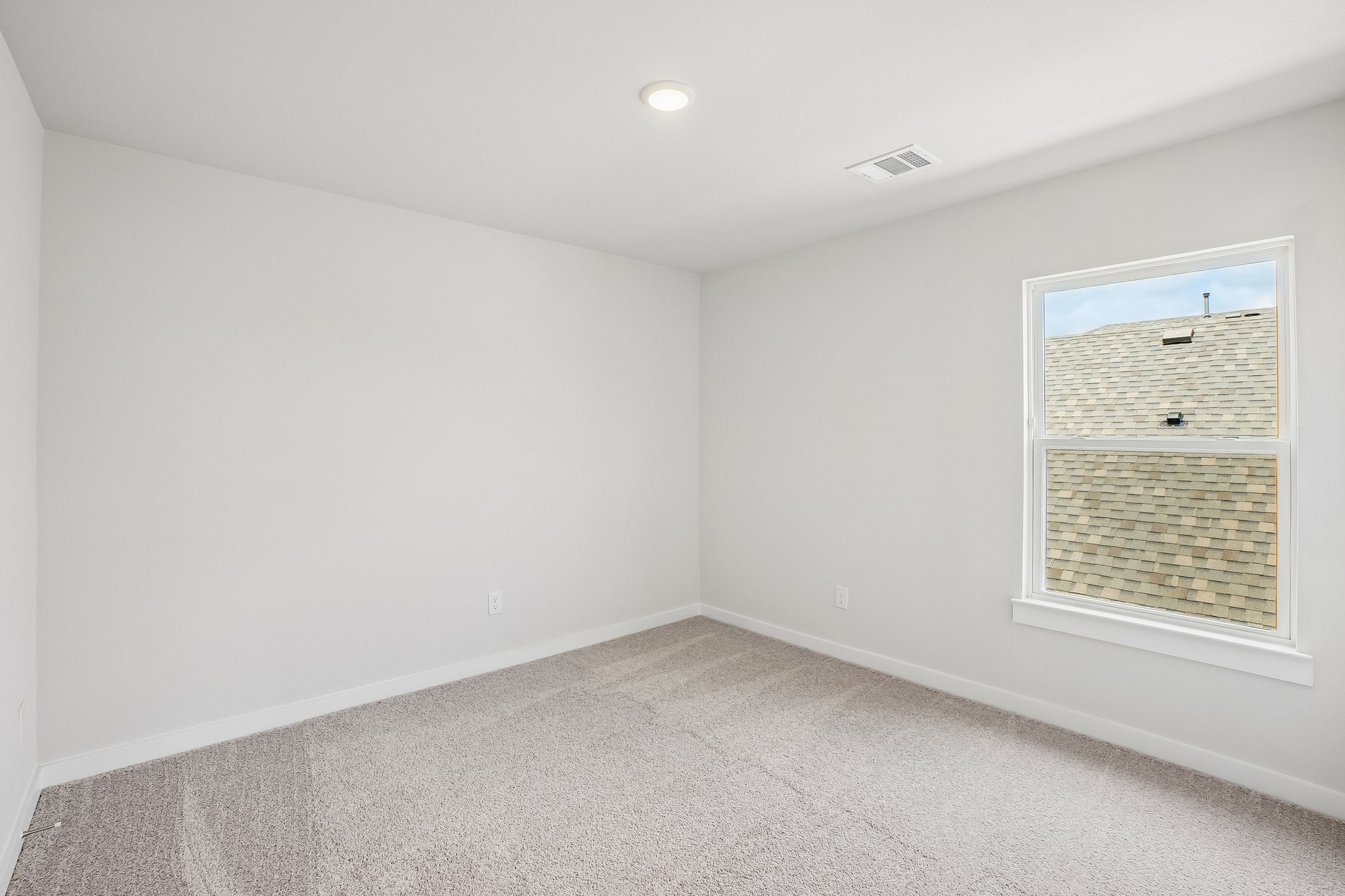 A room with a window and a white wall.