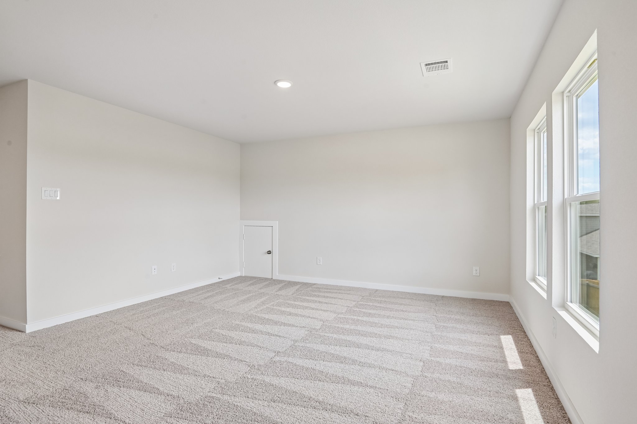 A room with a carpet and windows.