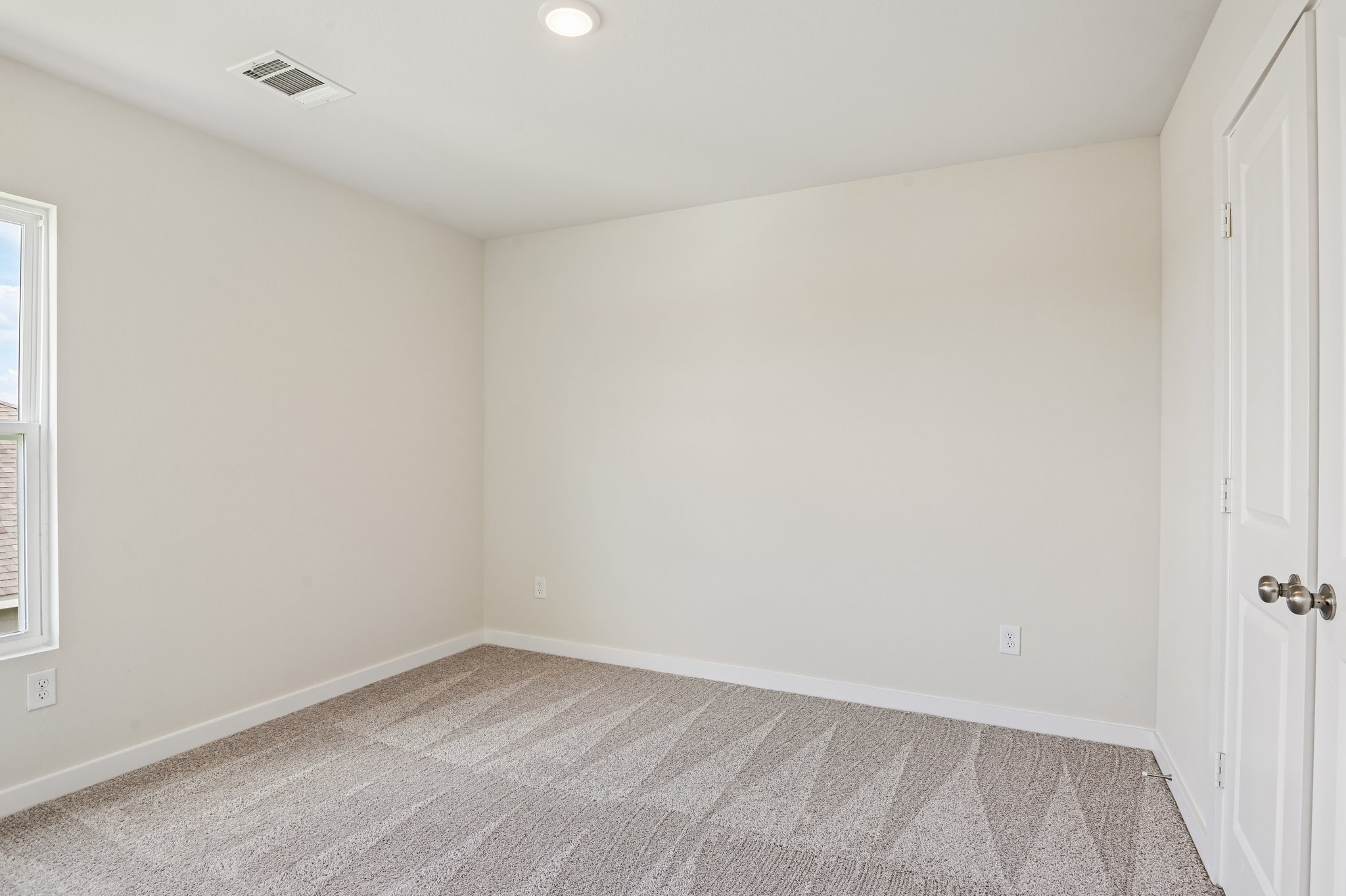 A room with a carpet and a door.