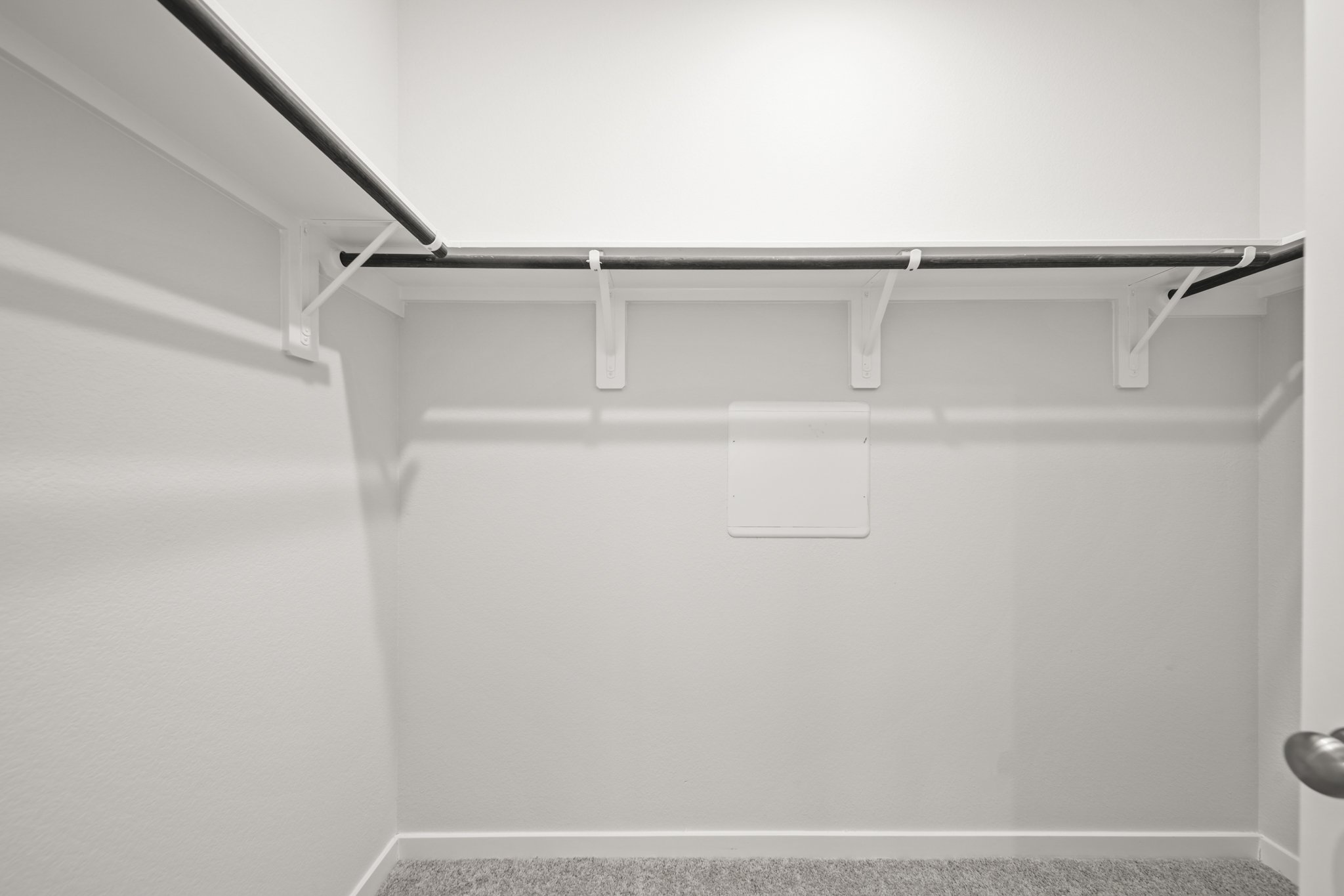 A white wall with a metal bar.