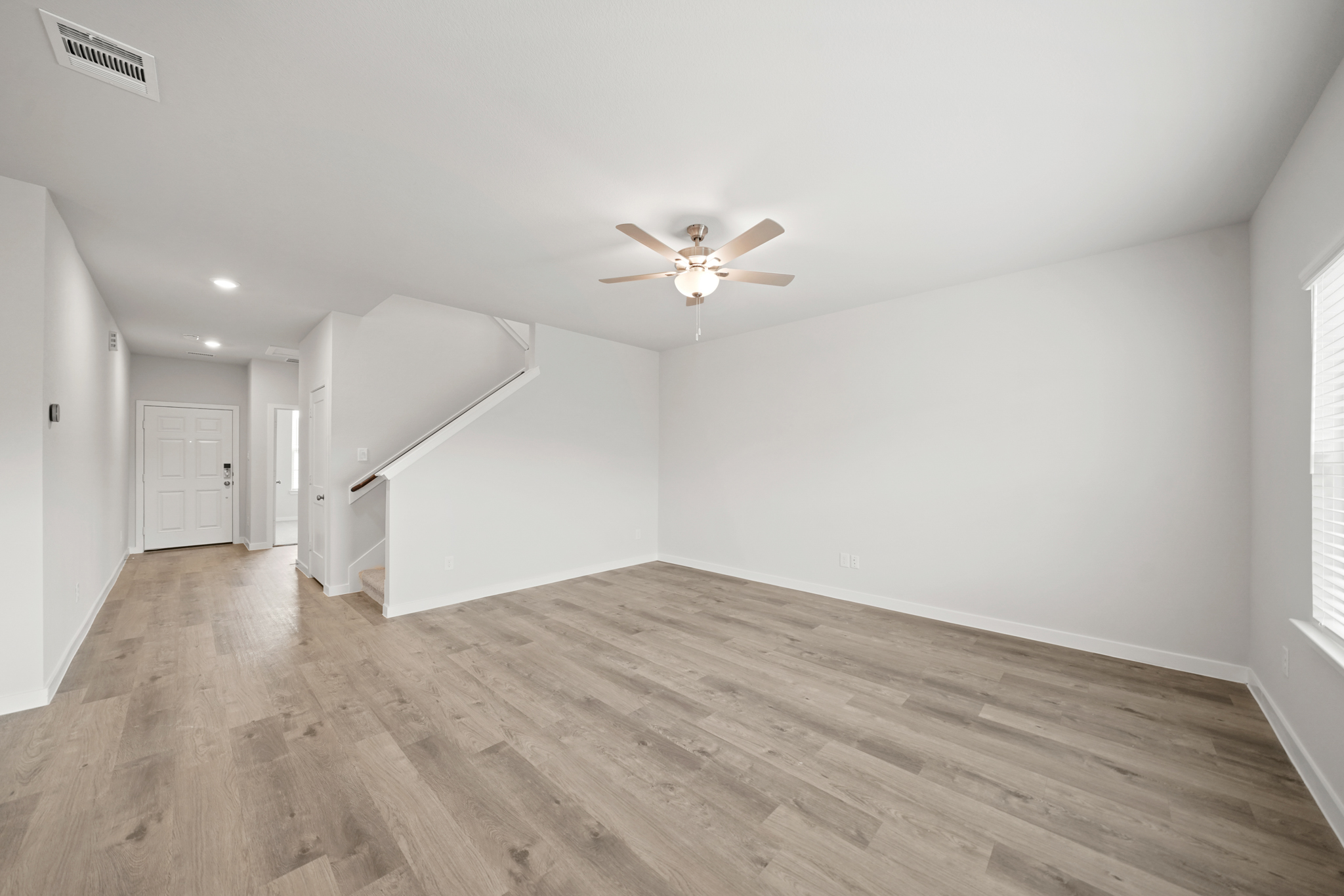 A room with a wood floor and a ceiling fan.