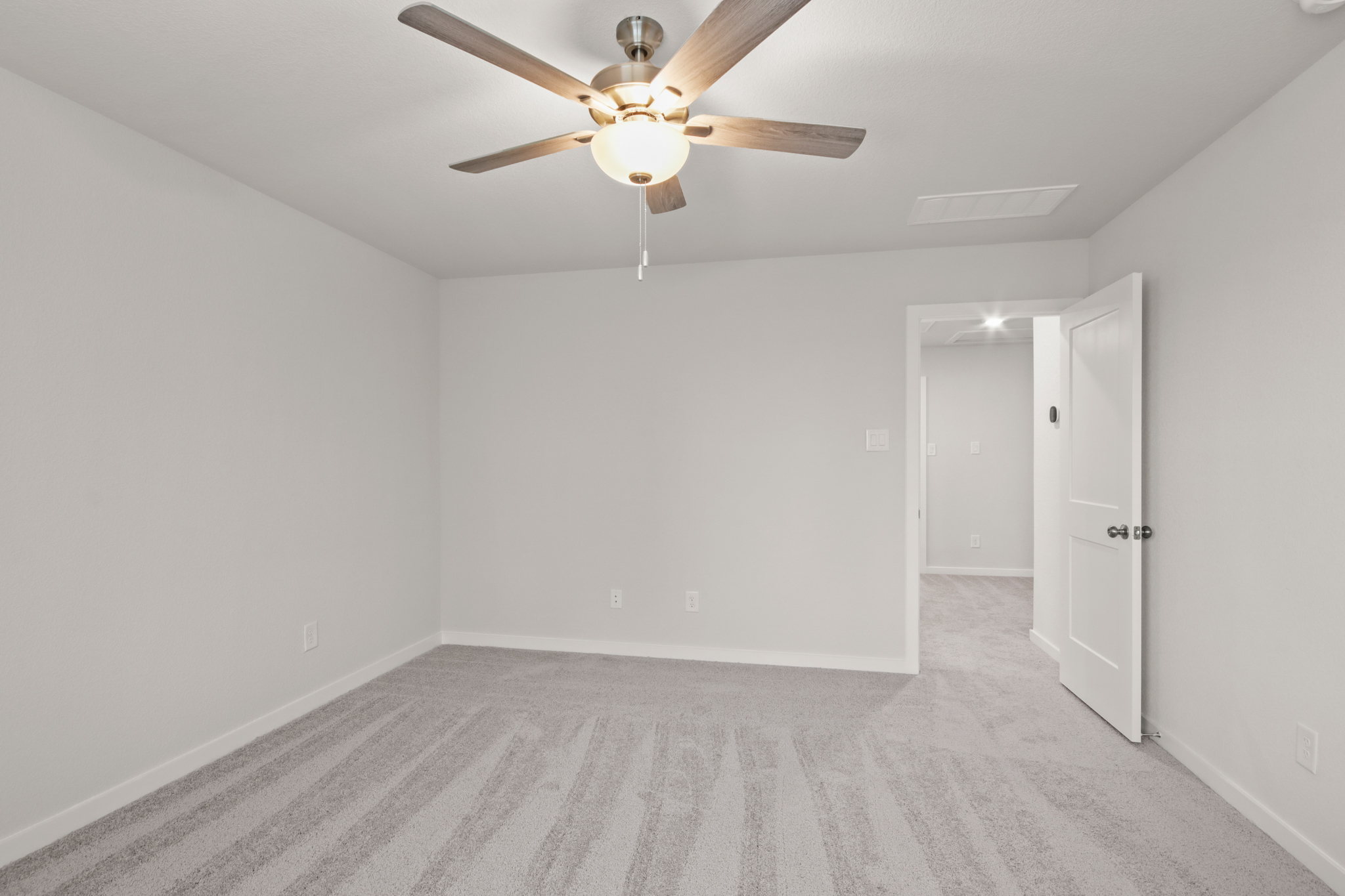 A room with a ceiling fan and white walls.