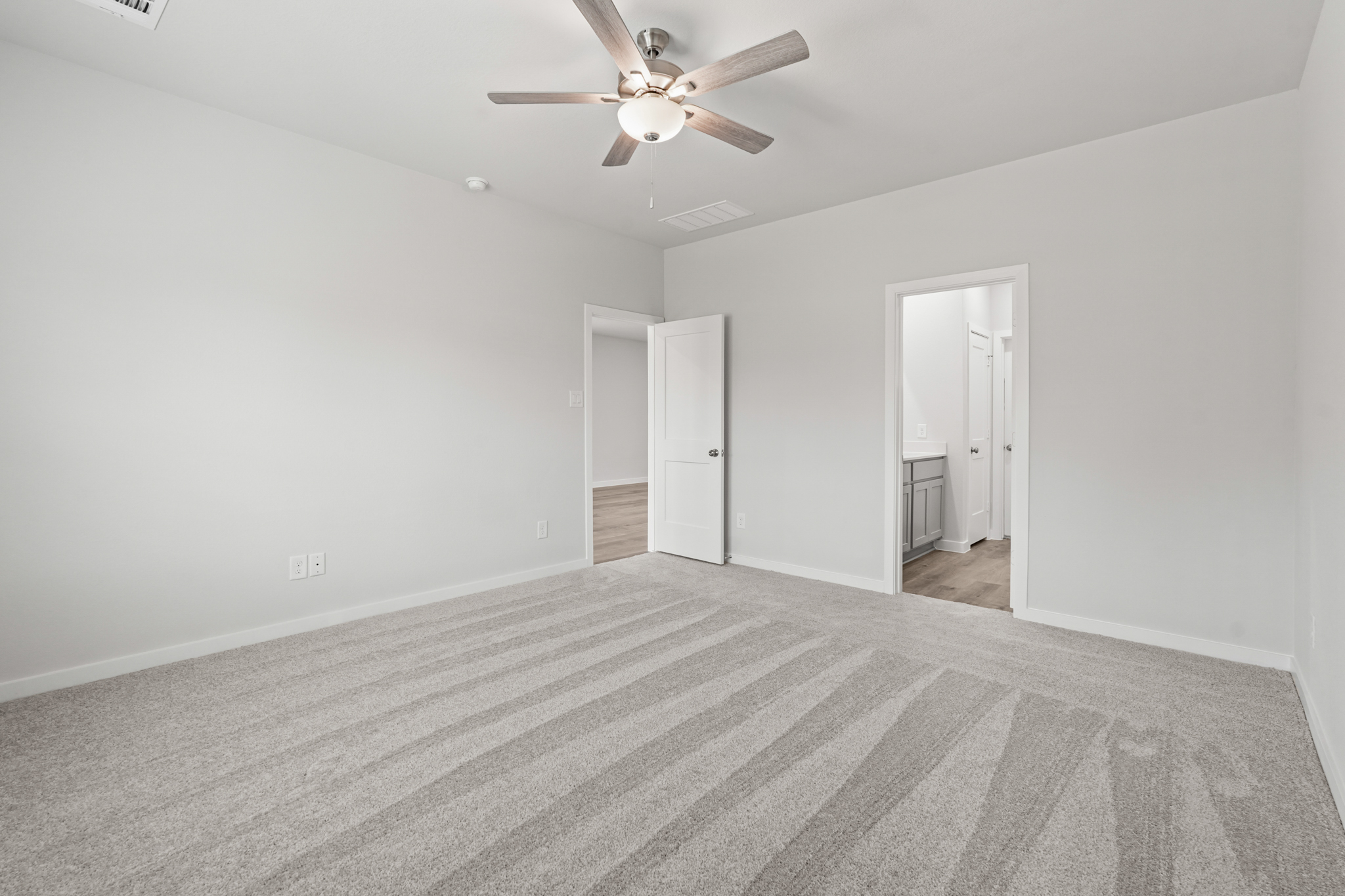 A room with a ceiling fan and a carpet.