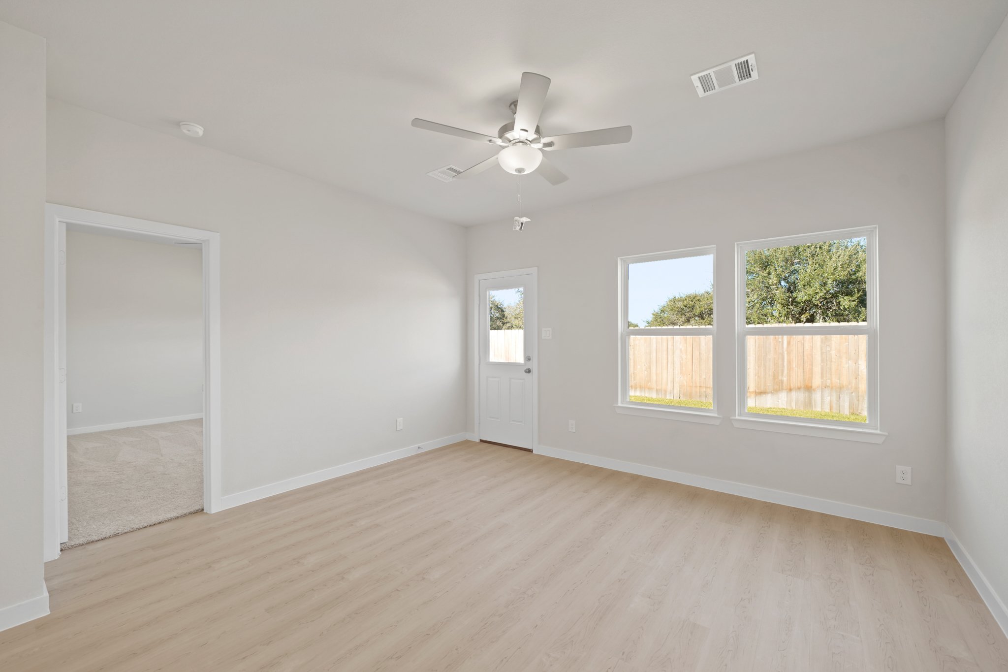 A room with a wood floor and a ceiling fan and a wood floor.