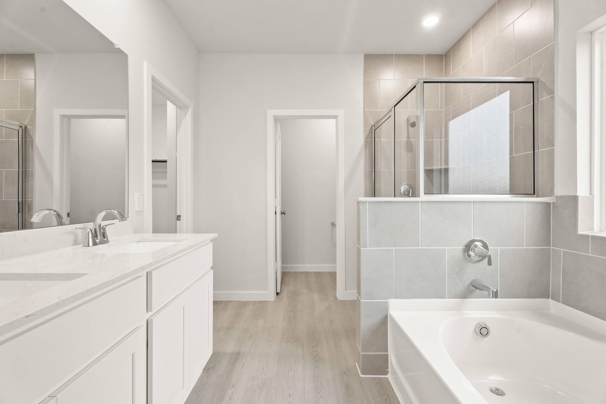 A bathroom with a tub sink and mirror.