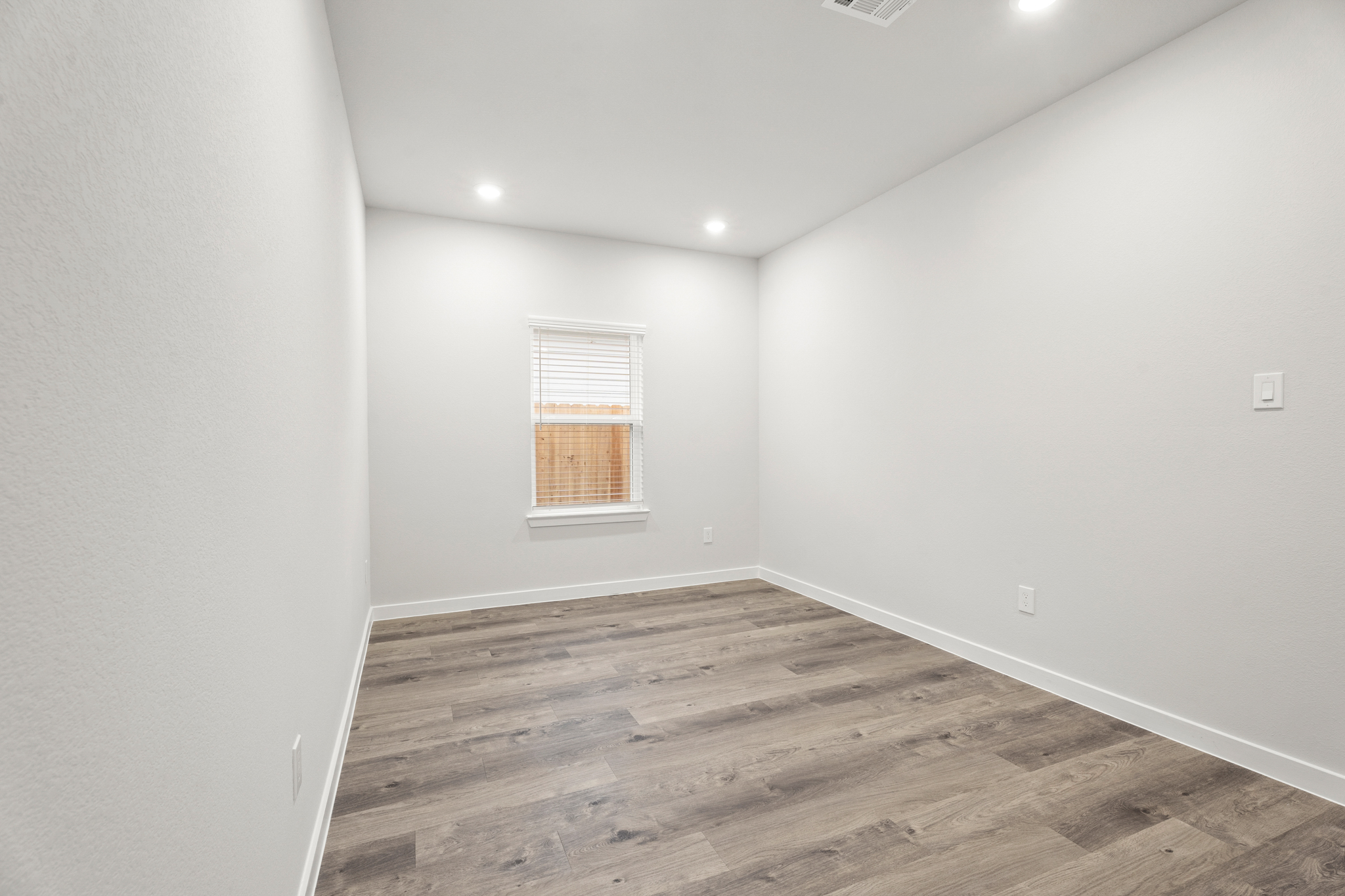 A room with a wood floor and a window.