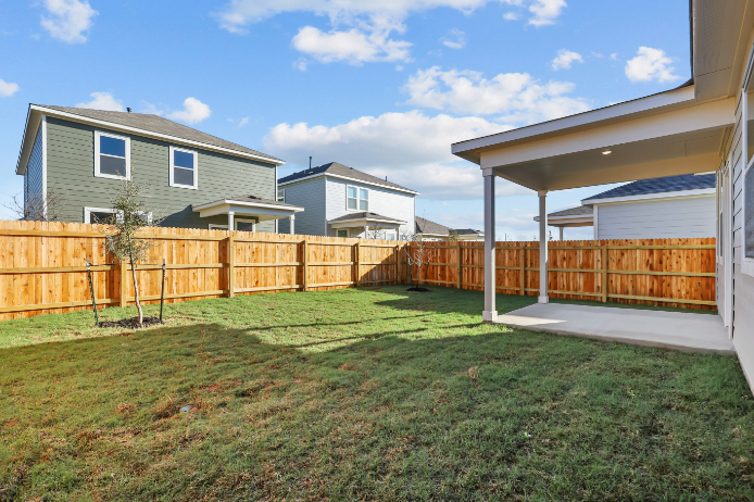 A fenced in yard with a house and trees.