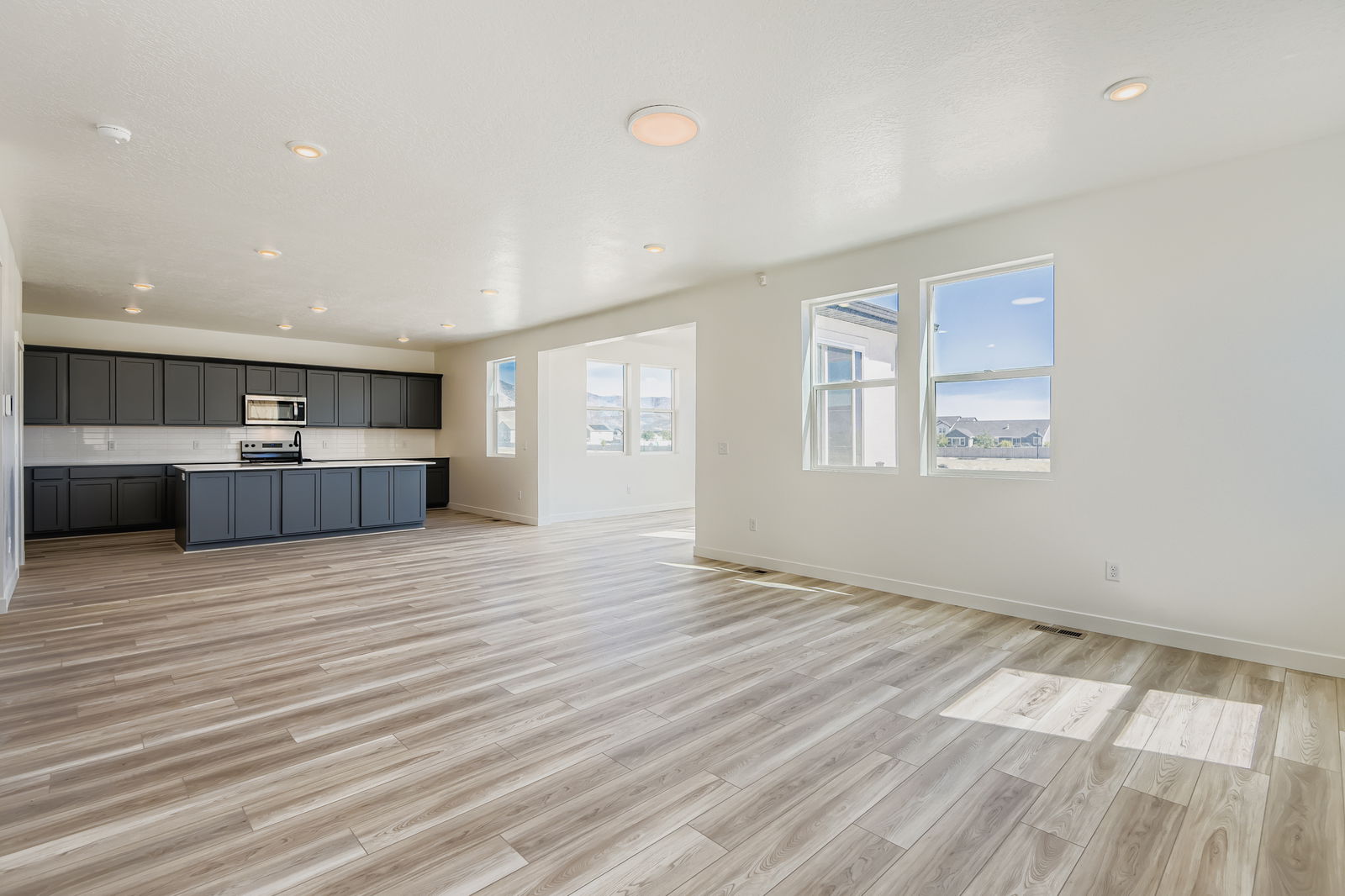 A large empty room with a wood floor and black cabinets.