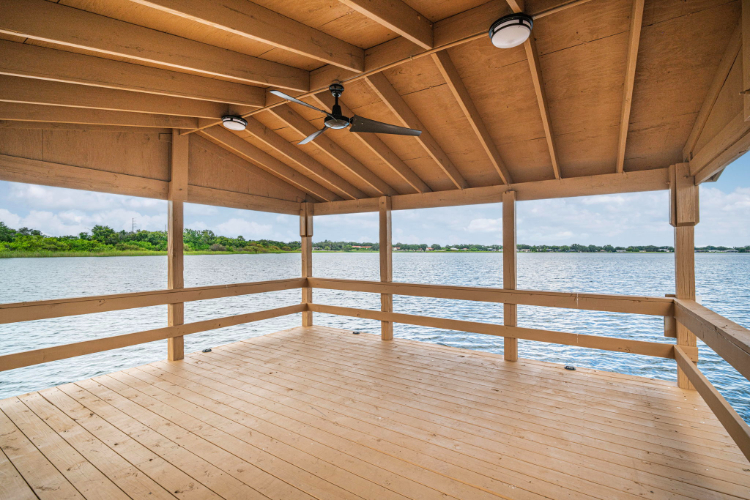 A wooden deck with a wood railing and a body of water.