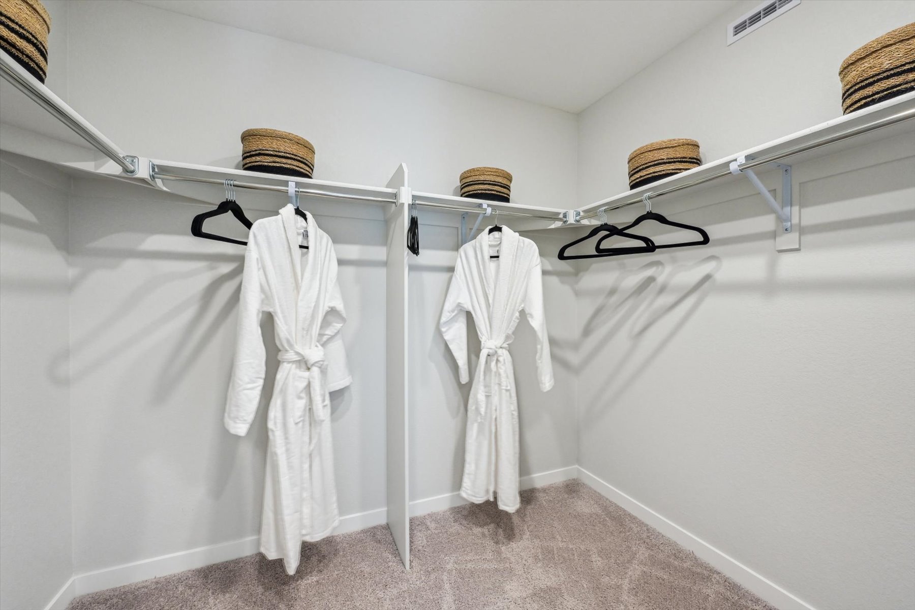 A white coat rack with a white robe and a basket on it.